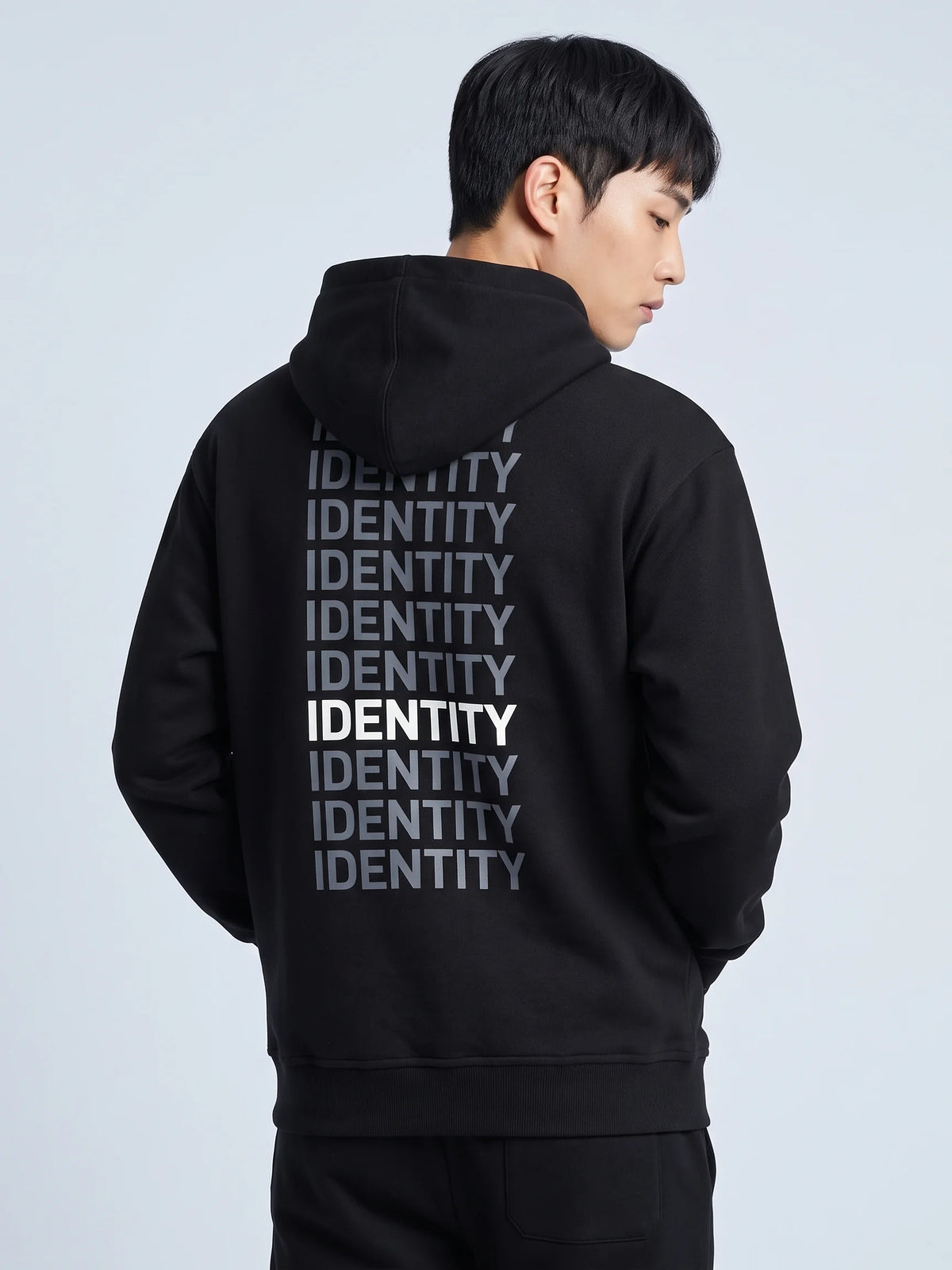 Black heavyweight hoodie in organic cotton, Unidentity Identity Hoodie, back close-up of the IDENTITY print worn by man, 390gsm UAE streetwear #color_black