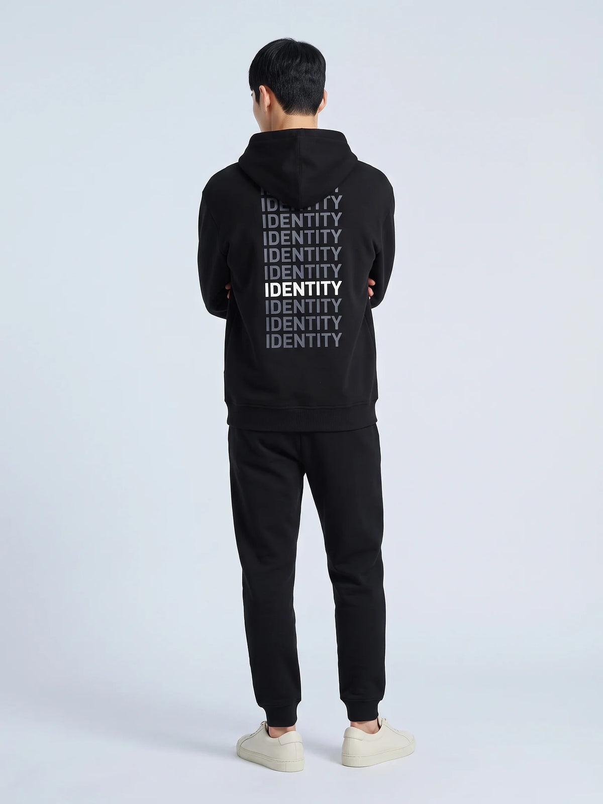 Black regular fit hoodie in organic cotton, Unidentity Identity Hoodie, back view of the IDENTITY print on a man with arms folded, sustainable fashion #color_black