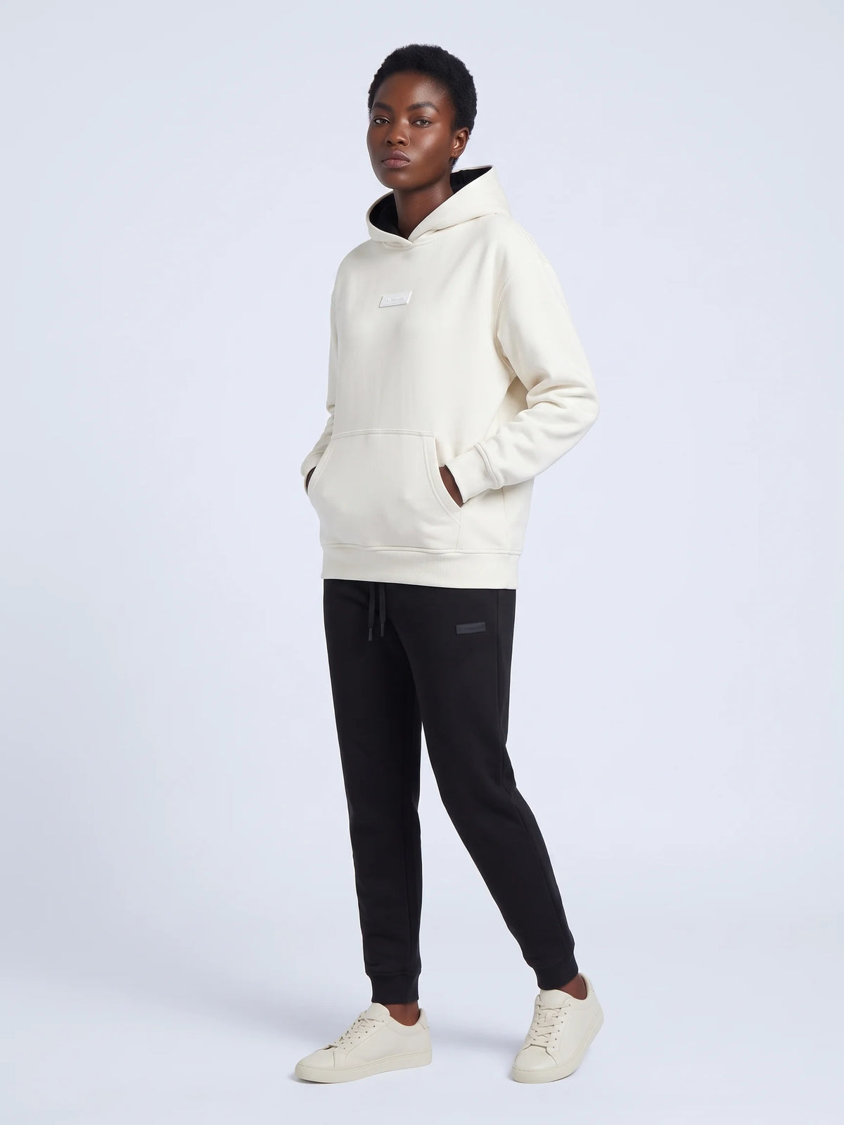 White organic cotton hoodie, Unidentity Identity Regular Fit Hoodie, full-length front view worn by woman, hands in kangaroo pocket, UAE streetwear #color_white
