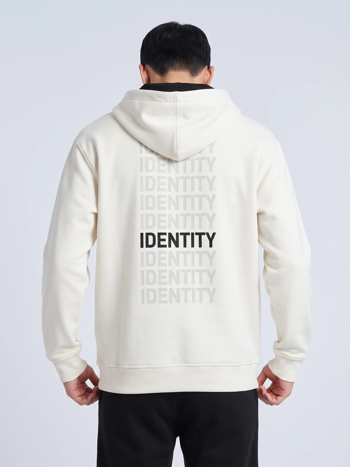 White regular fit hoodie, Unidentity Identity Regular Fit Hoodie, back close-up of the IDENTITY print and ribbed hem worn by man, streetwear #color_white
