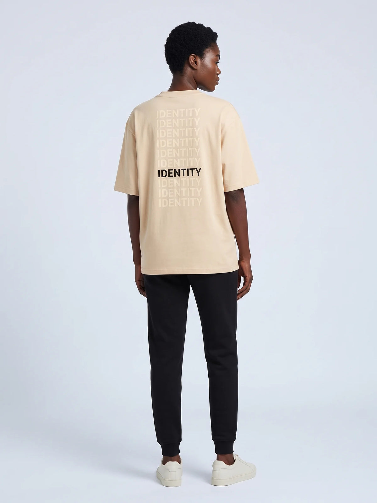 Beige oversized t-shirt, Unidentity Identity Tee, full-length back view of the IDENTITY print worn by woman, sustainable streetwear #color_beige