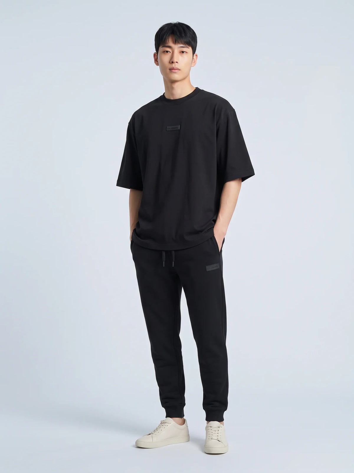 Black oversized t-shirt in organic cotton, Unidentity Identity Tee, full-length front view of an all-black look with Core Regular Fit Joggers, 210gsm #color_black
