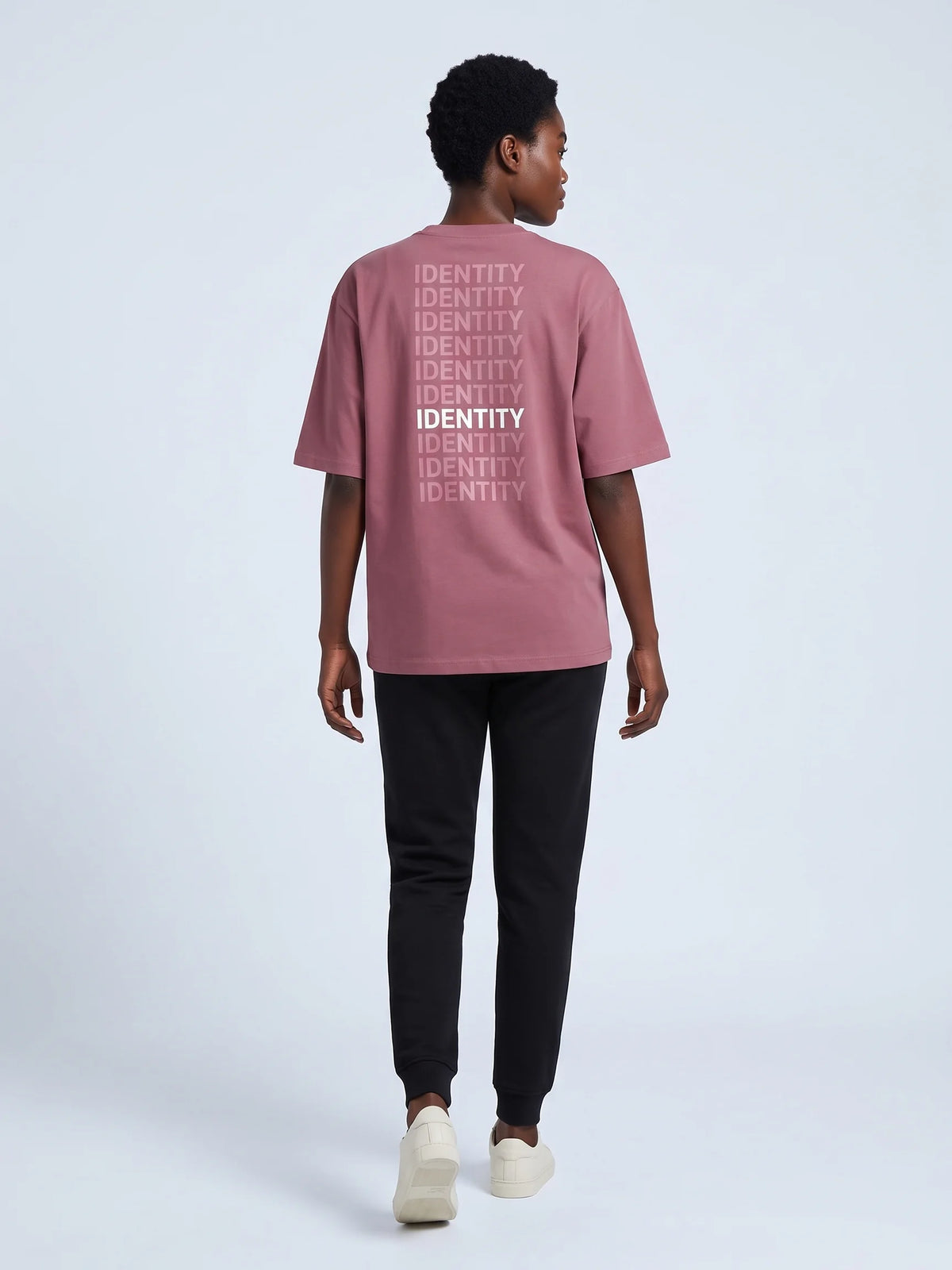 Plum oversized t-shirt in organic cotton, Unidentity Identity Tee, back view of the IDENTITY print worn by woman walking, Dubai streetwear #color_plum