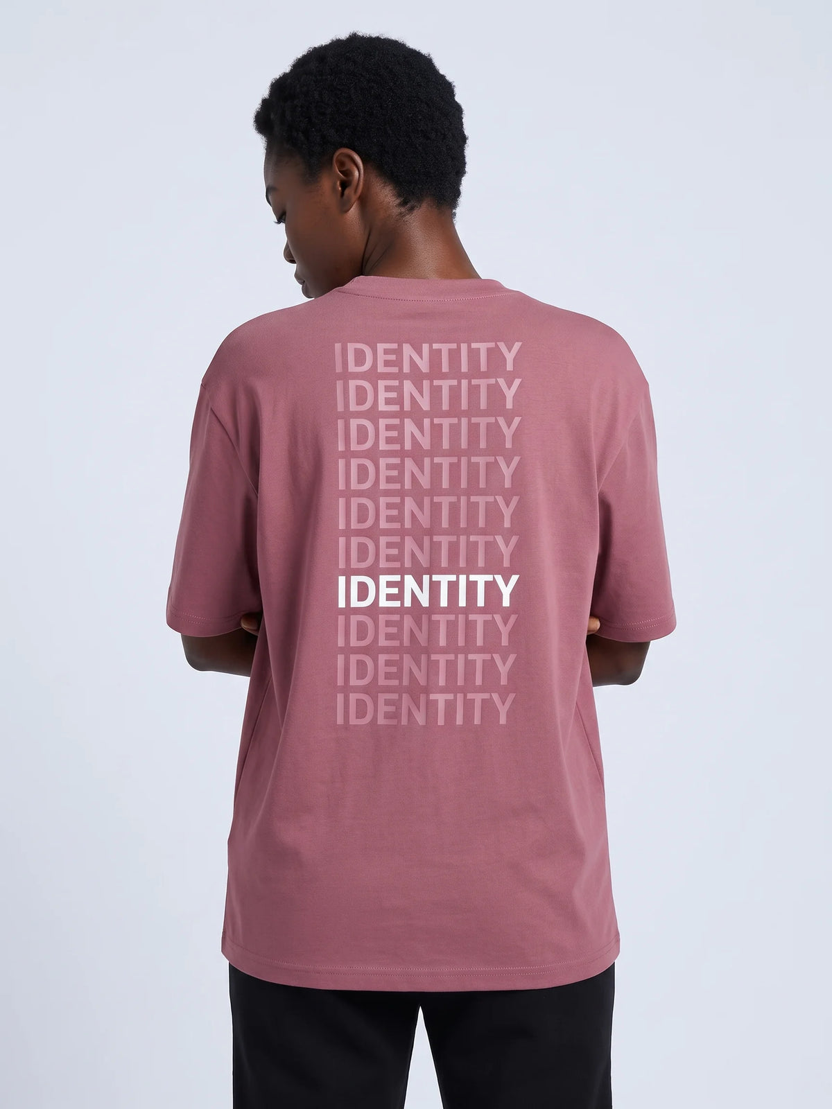 Plum oversized t-shirt, Unidentity Identity Oversized Tee, back close-up of the tonal IDENTITY repeat print worn by woman with arms folded, streetwear #color_plum