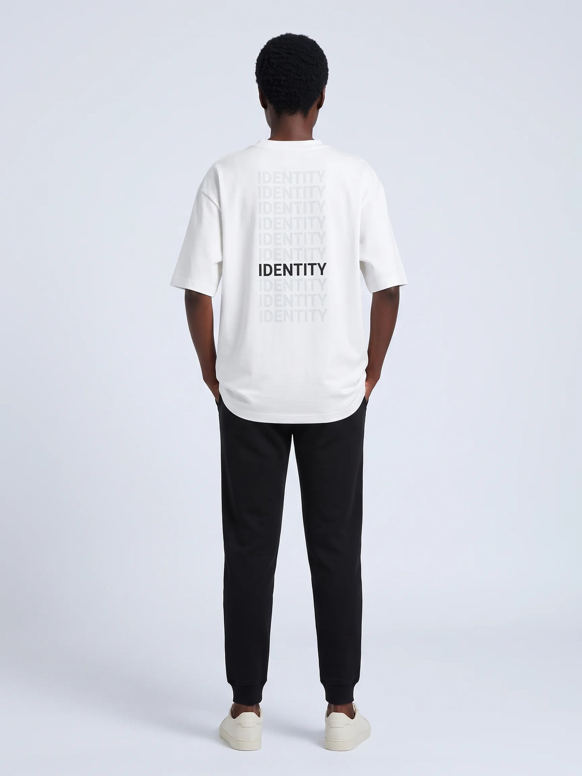 White oversized t-shirt in organic cotton, Unidentity Identity Tee, full-length back view of the IDENTITY print worn by woman, Dubai streetwear #color_white