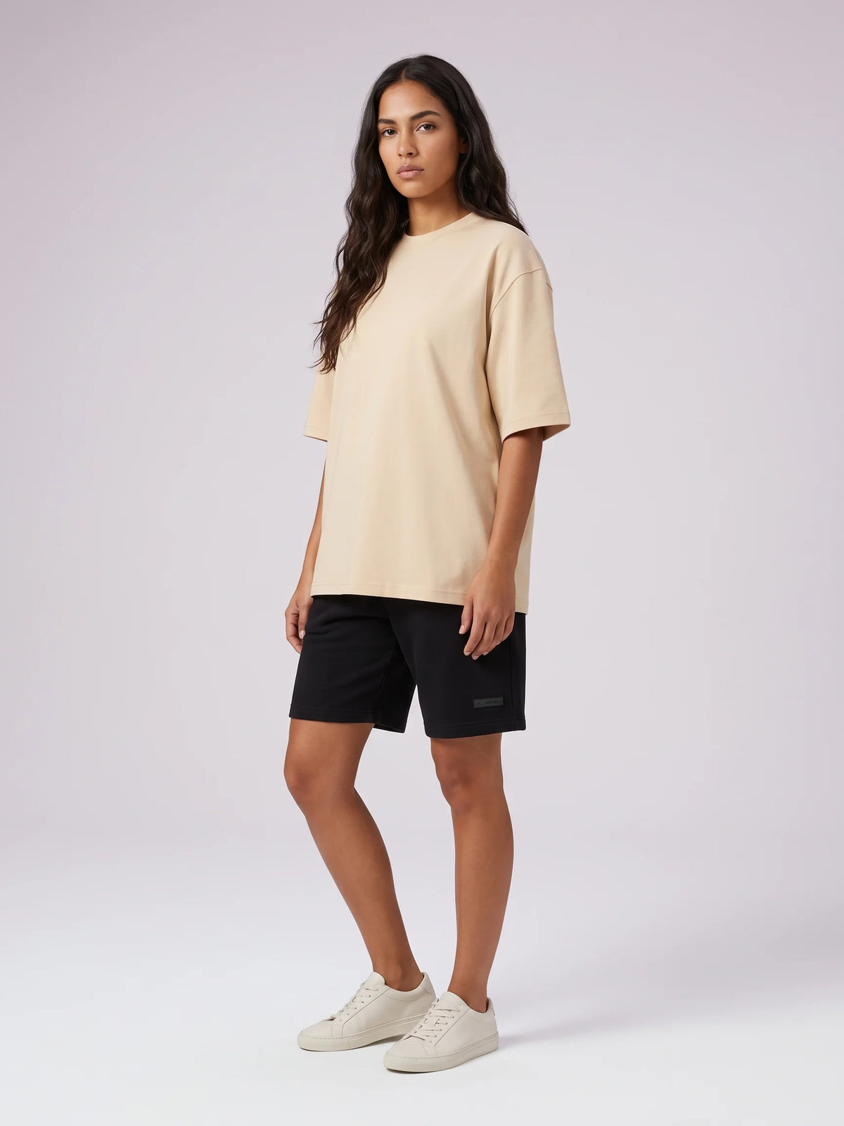 Beige organic cotton t-shirt, Unidentity Foundation Oversized Tee, full-length front view worn by woman with black Core shorts, streetwear #color_beige