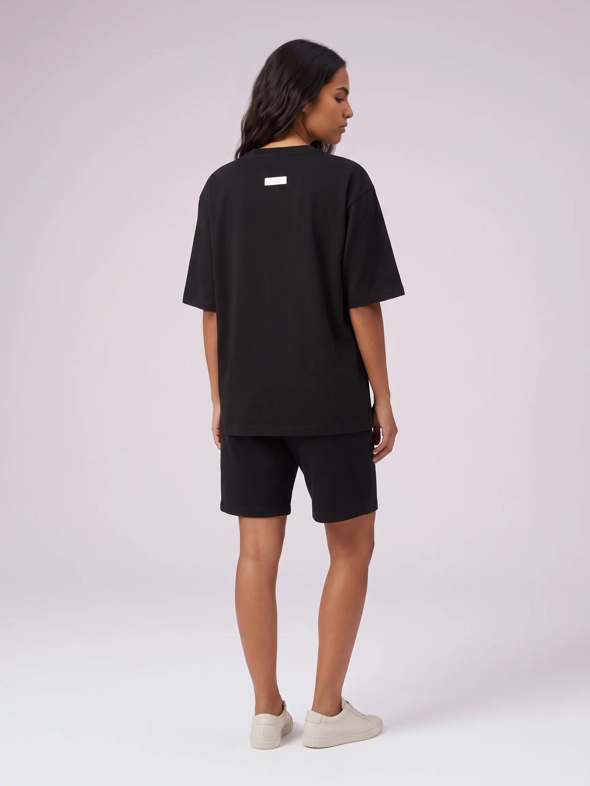 Black heavyweight oversized t-shirt, Unidentity Foundation Oversized Tee, full-length back view worn by woman showing the minimal 3D patch, 210gsm #color_black