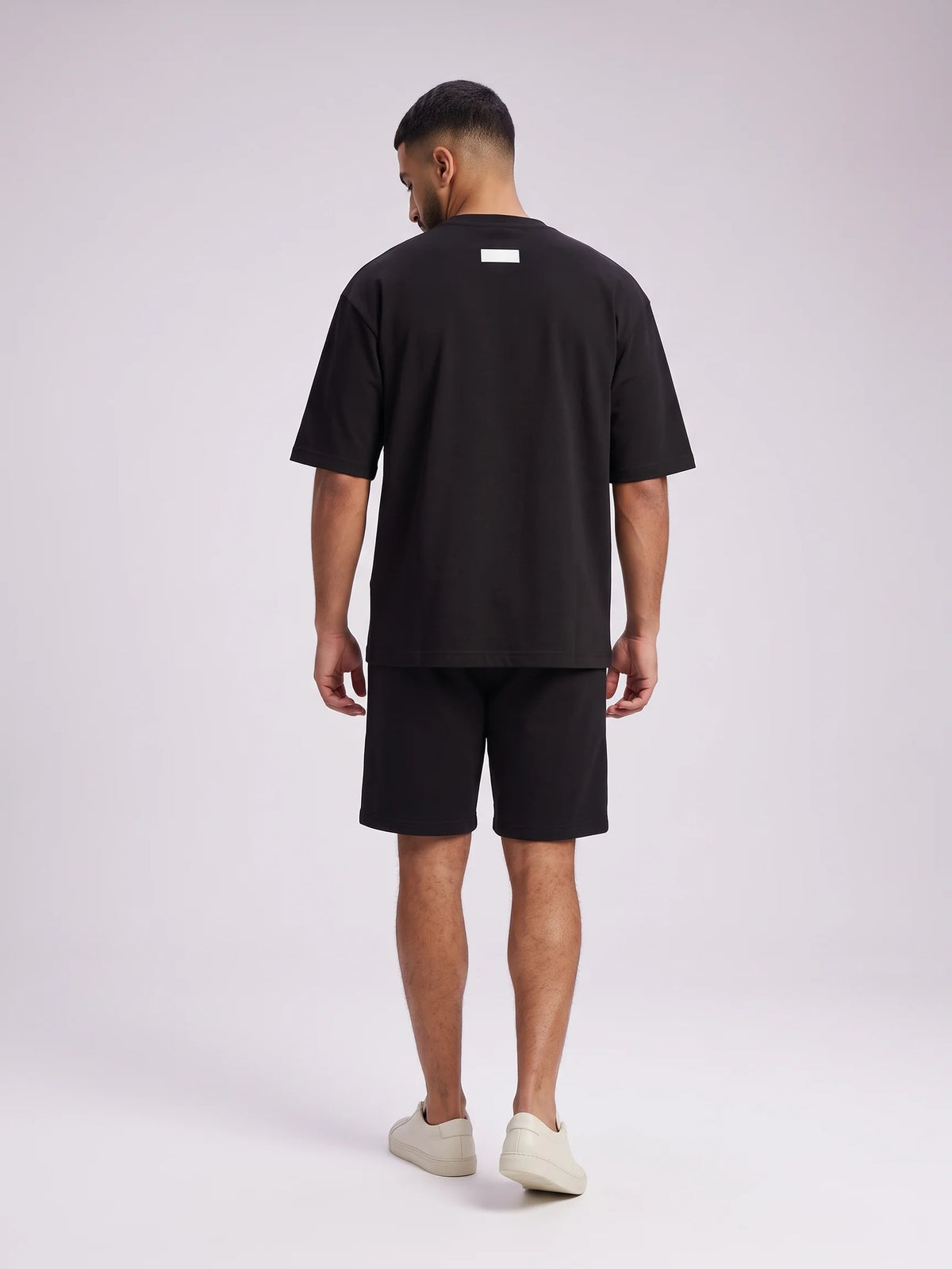 Black organic cotton t-shirt, Unidentity Foundation Oversized Tee, full-length back view worn by man with Core shorts, UAE streetwear #color_black