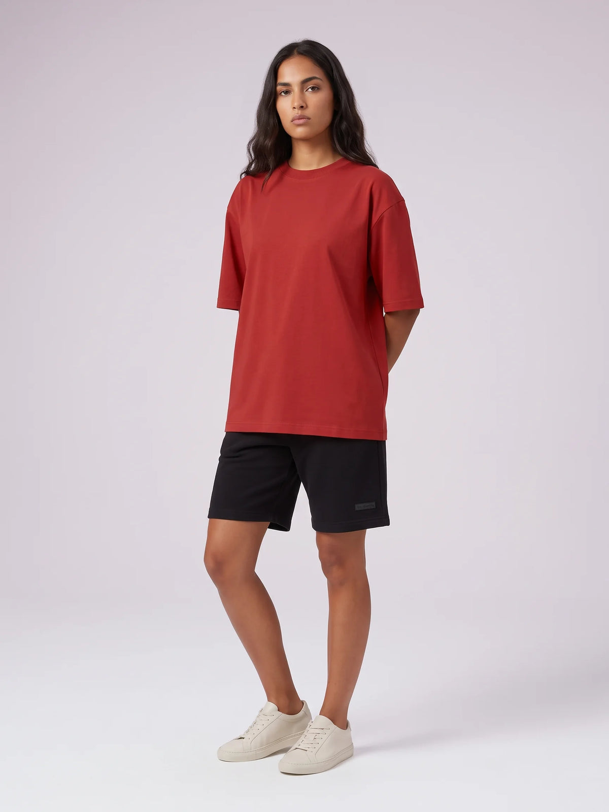 Red organic cotton t-shirt, Unidentity Foundation Oversized Tee, full-length front view worn by woman with black shorts, sustainable fashion #color_red
