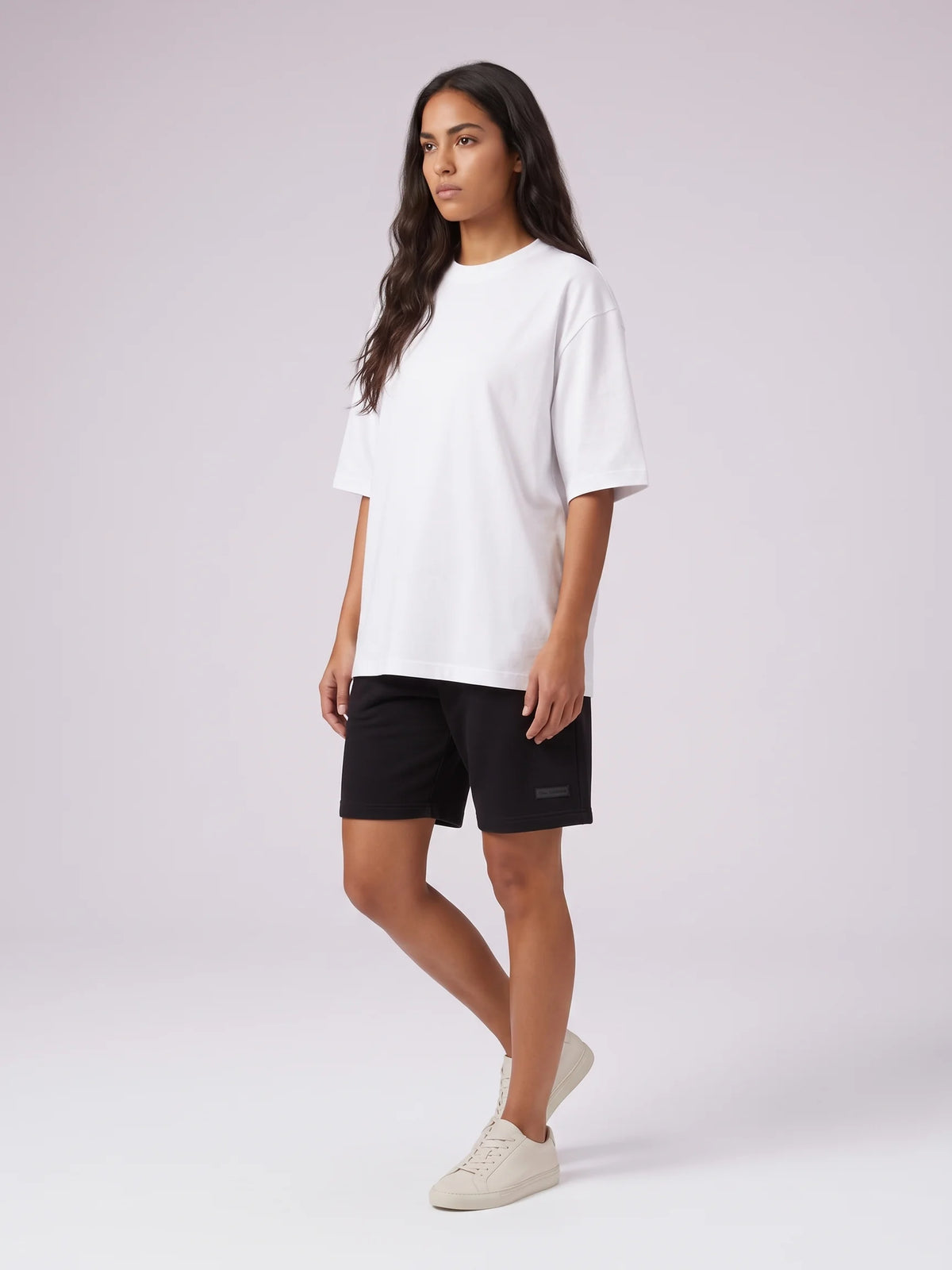 White oversized t-shirt in organic cotton, Unidentity Foundation Tee, full-length front view worn by woman with black Core shorts, streetwear #color_white