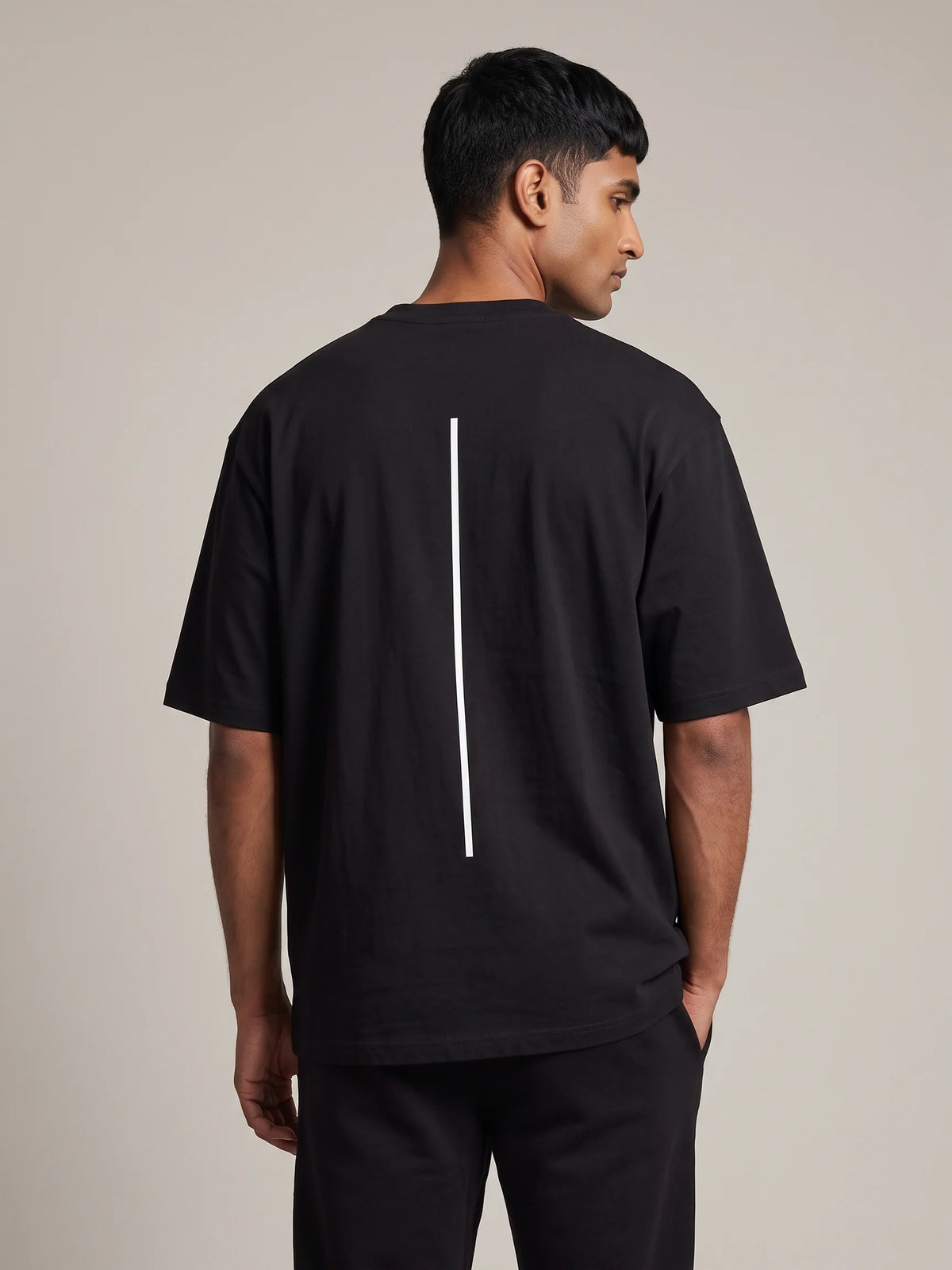 Black oversized t-shirt, Unidentity Trace Oversized Tee, close back view worn by man showing the white vertical line print, organic cotton #color_black