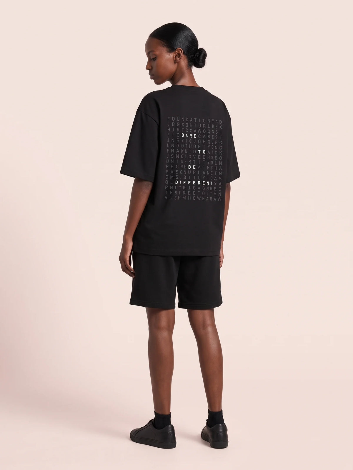 Black heavyweight oversized t-shirt, Unidentity Dare Oversized Tee, three-quarter back view worn by woman showing the word search print, 210gsm #color_black