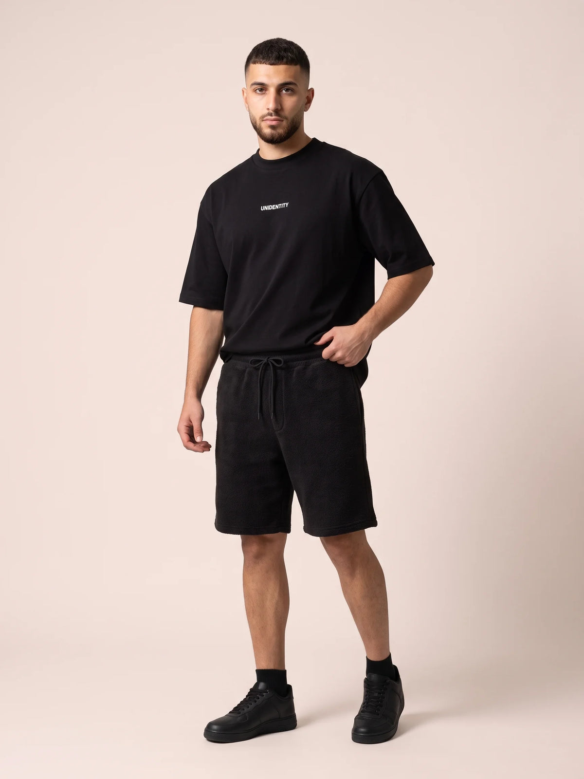 Black oversized t-shirt, Unidentity Dare Tee, full-length front view worn by man with Core Regular Fit Shorts, streetwear from the UAE #color_black