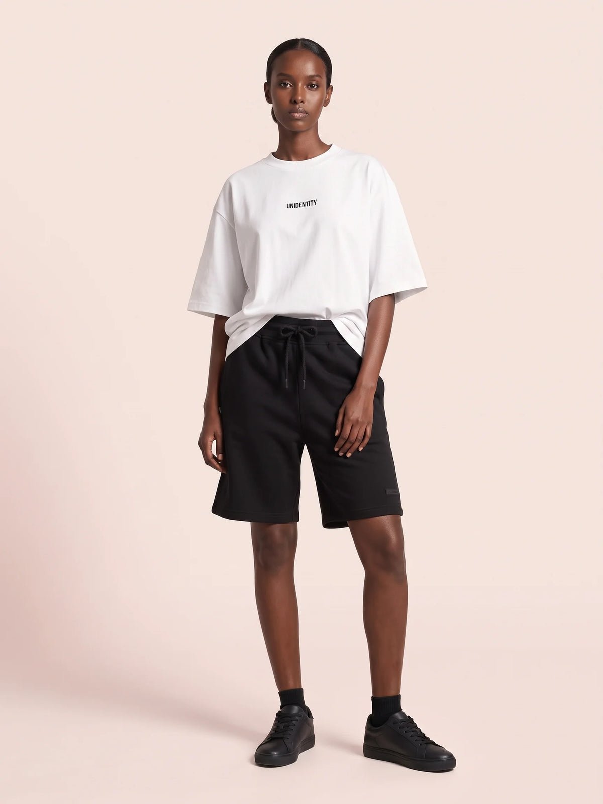 White oversized t-shirt, Unidentity Dare Tee, full-length front view worn by woman with black Core Regular Fit Shorts, UAE streetwear #color_white