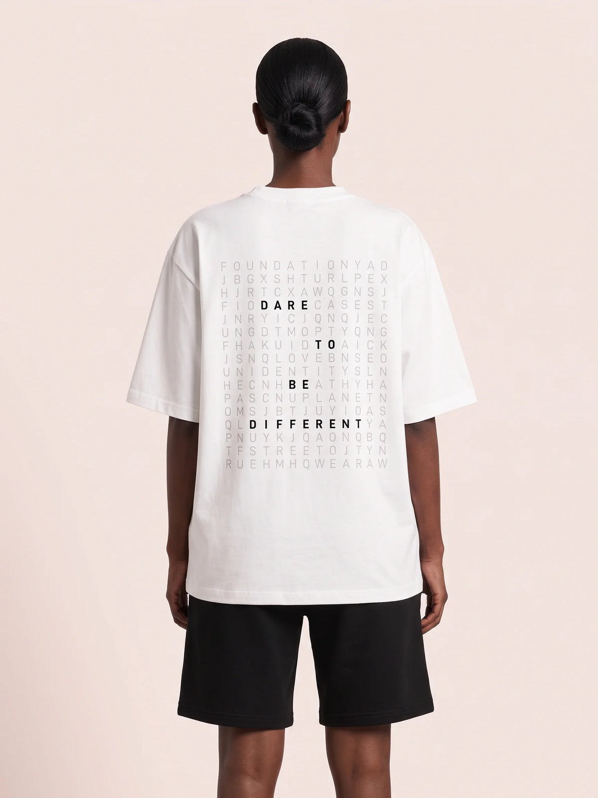 White oversized t-shirt, Unidentity Dare Oversized Tee, back view worn by woman showing the DARE TO BE DIFFERENT word search print, organic cotton #color_white
