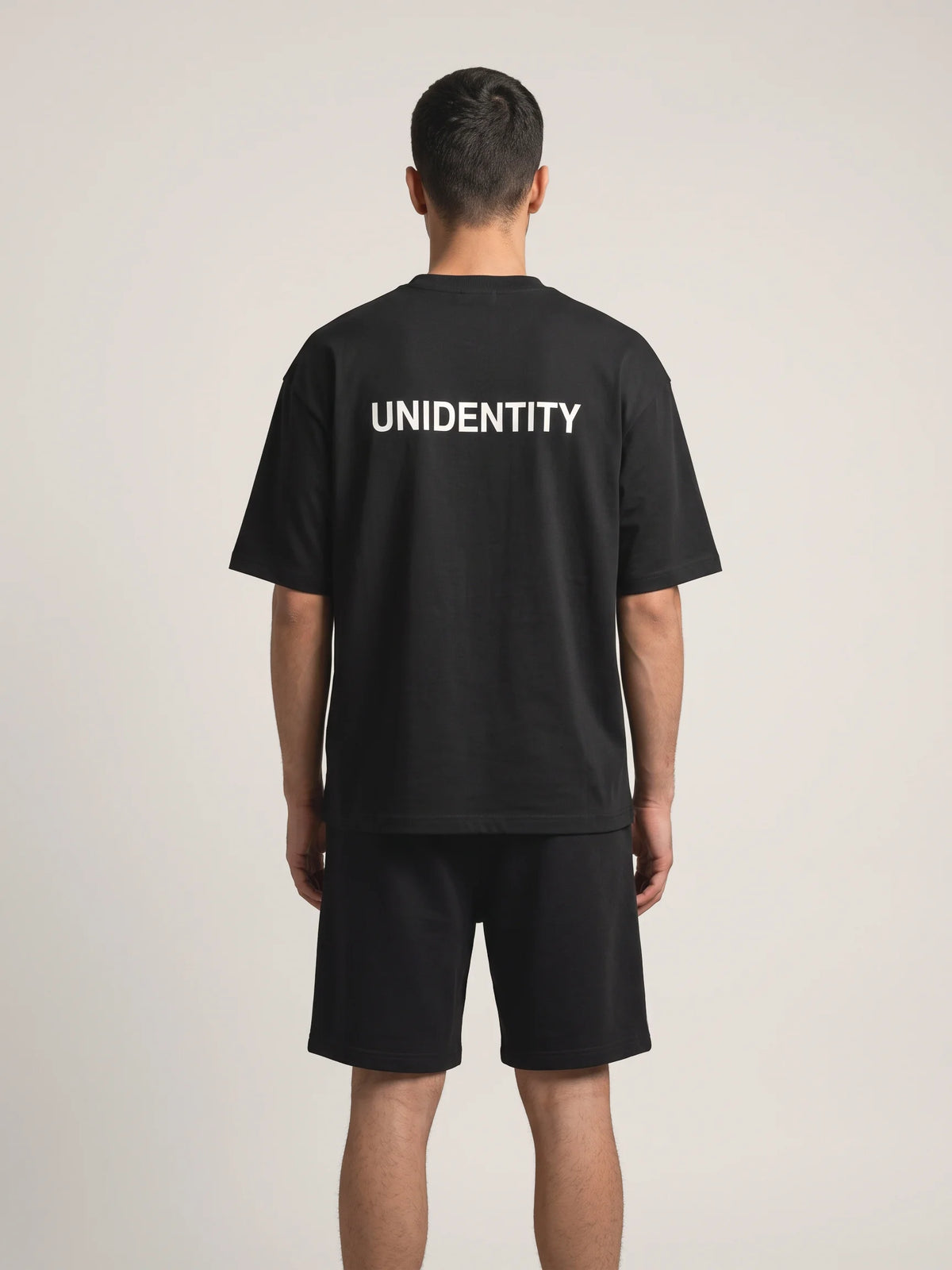 Black oversized t-shirt, Unidentity You Oversized Tee, back view worn by man showing the white UNIDENTITY logo, sustainable streetwear #color_black