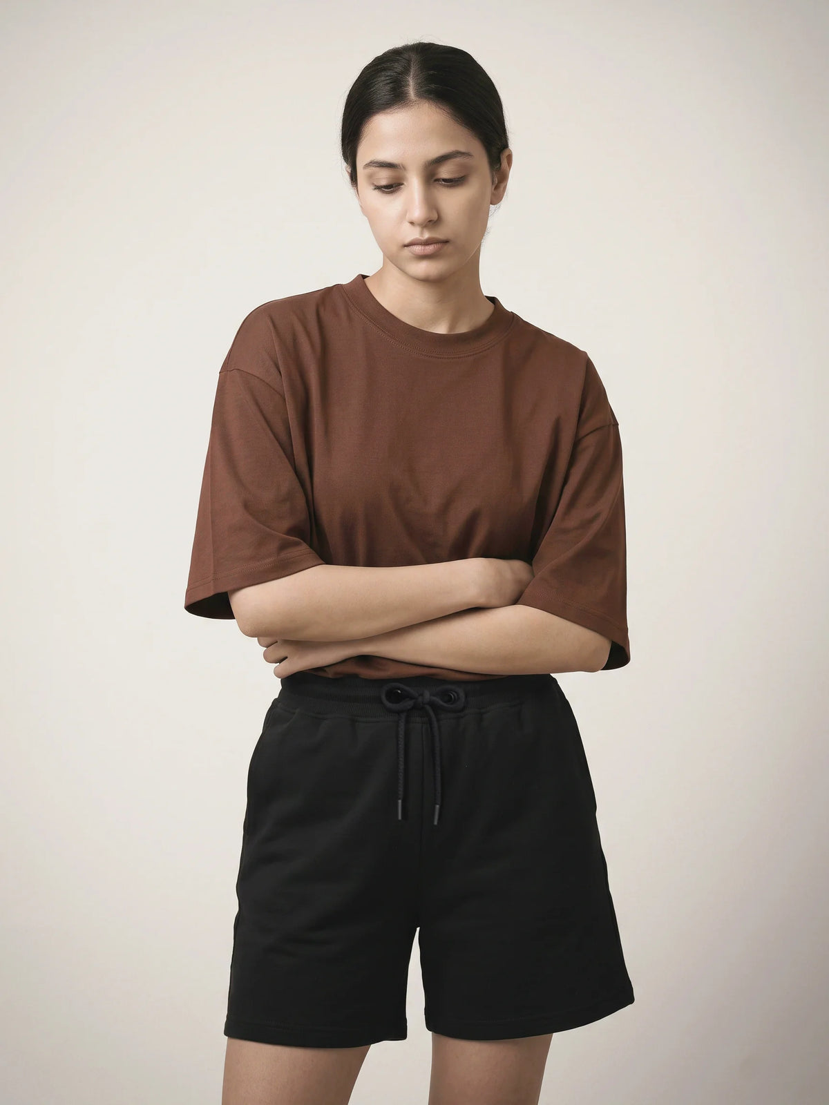 Chocolate oversized t-shirt, Unidentity You Tee, front view worn by woman with arms crossed and black Core Regular Fit Shorts, UAE streetwear #color_chocolate