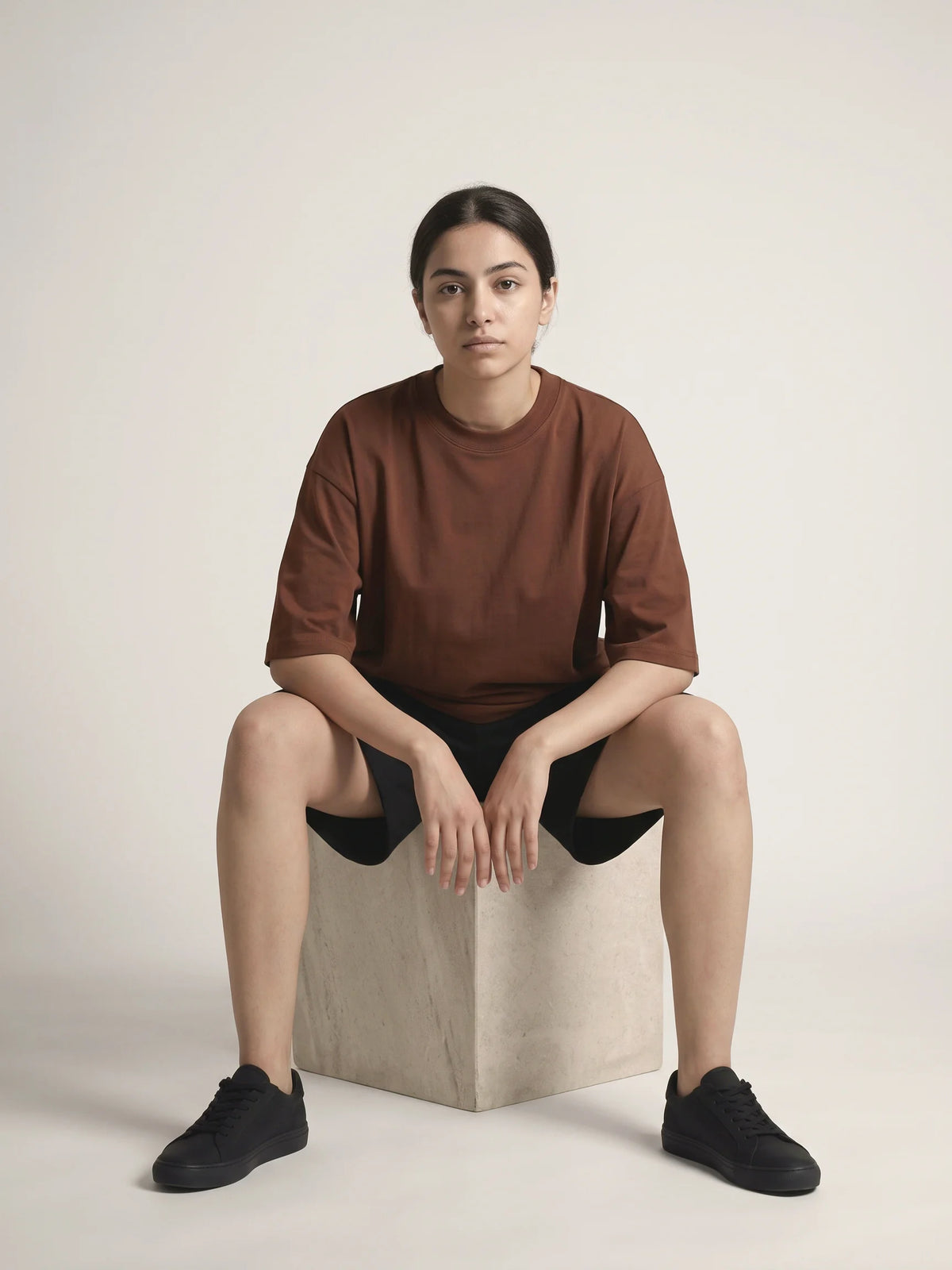 Chocolate oversized t-shirt in organic cotton, Unidentity You Oversized Tee, full-length front view of a seated woman, sustainable streetwear #color_chocolate