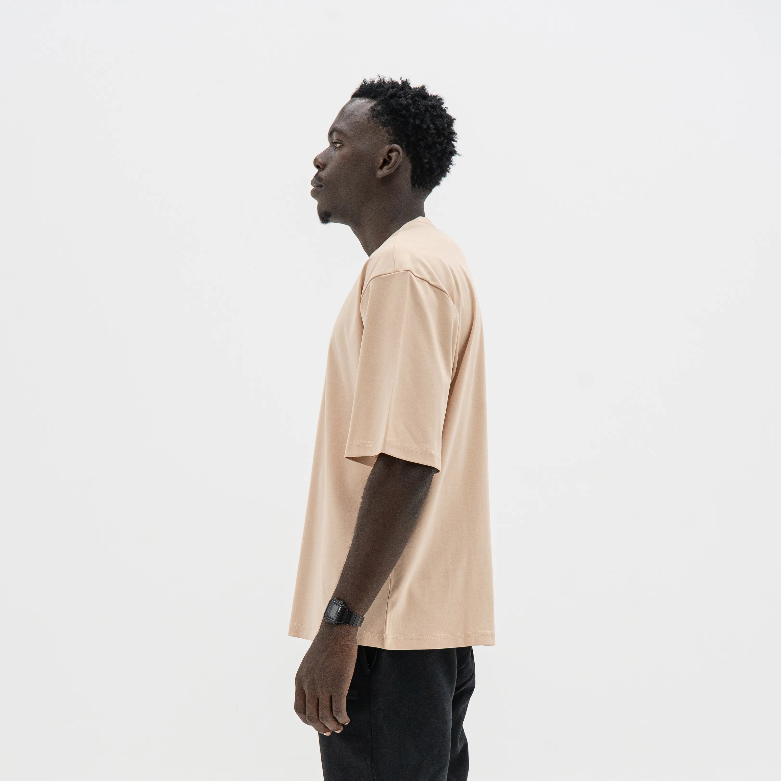 Man wearing a beige t-shirt and black pants on a white background. #color_beige