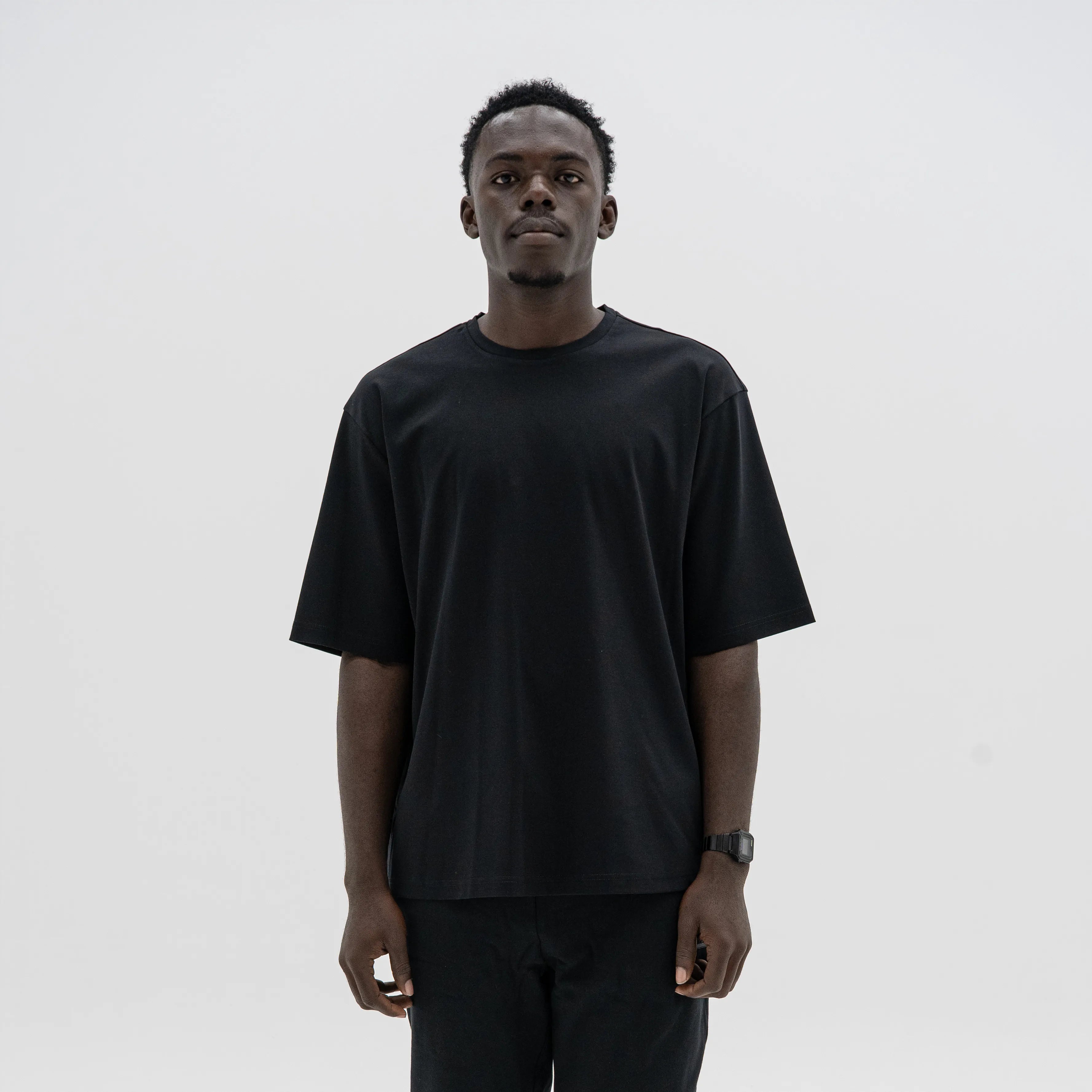 Man wearing a black t-shirt against a plain background. #color_black