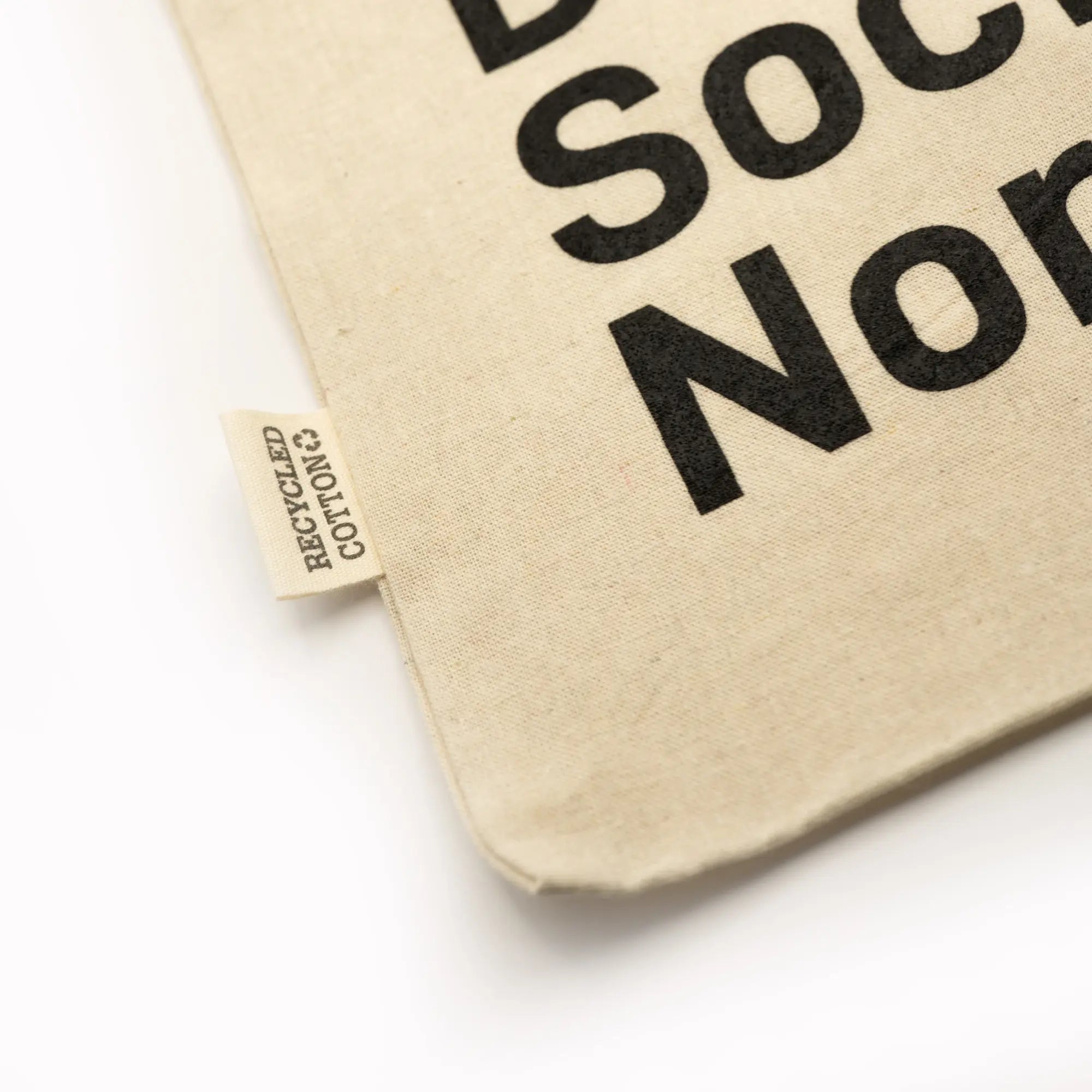 Beige fabric pouch with black text and a visible recycled cotton tag 