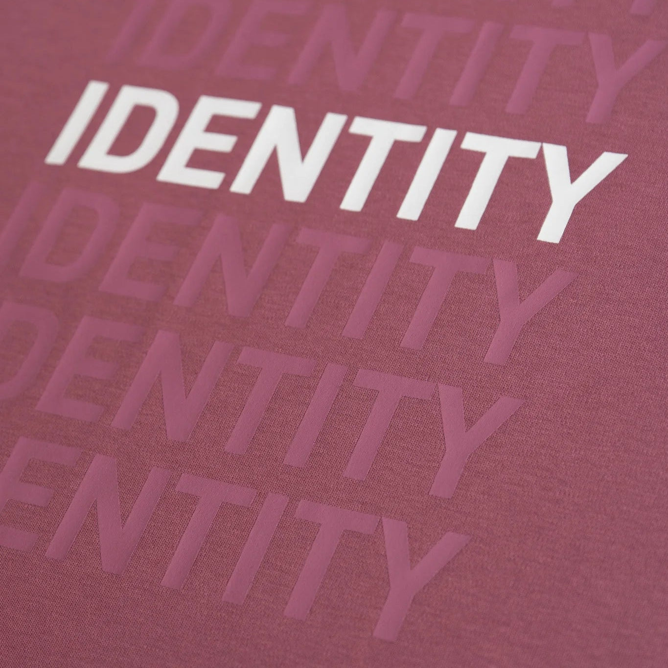 Close-up of a plum fabric with 'IDENTITY' printed repeatedly in white. #color_plum