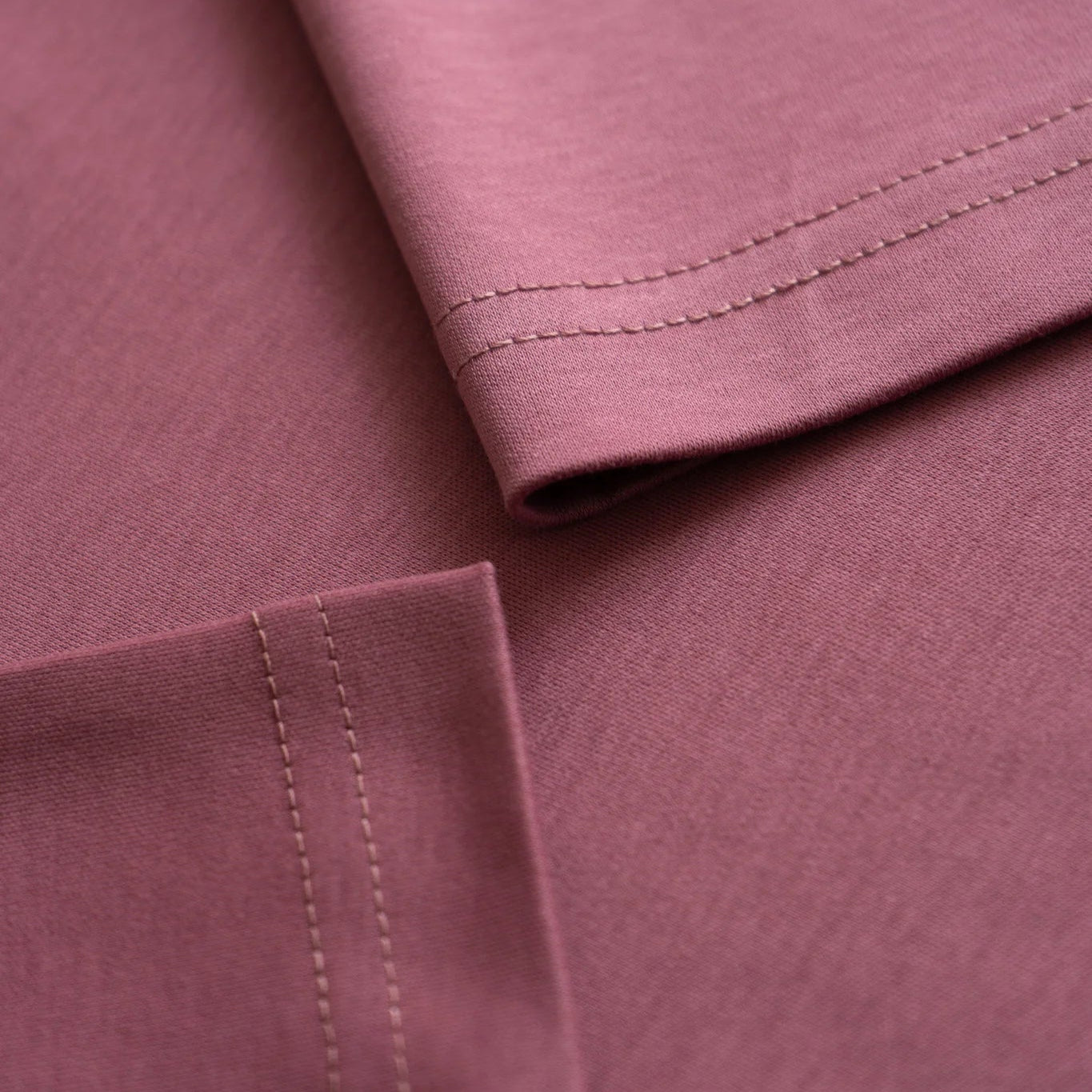 Close-up of a folded plum fabric with visible stitching. #color_plum