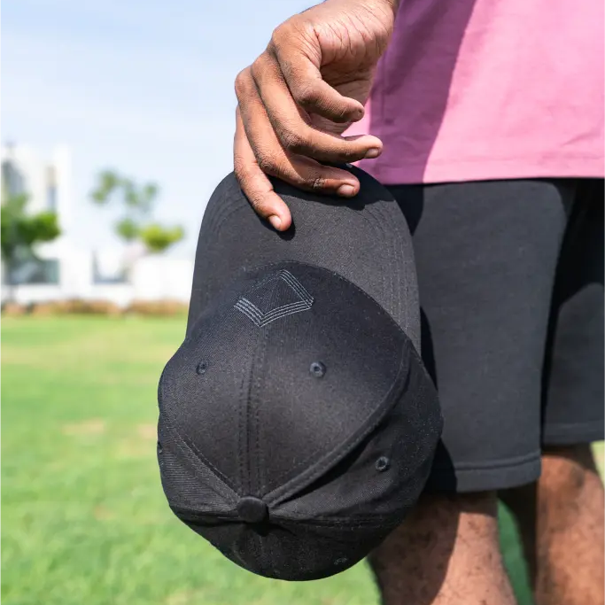 Person holding black baseball cap outdoors 