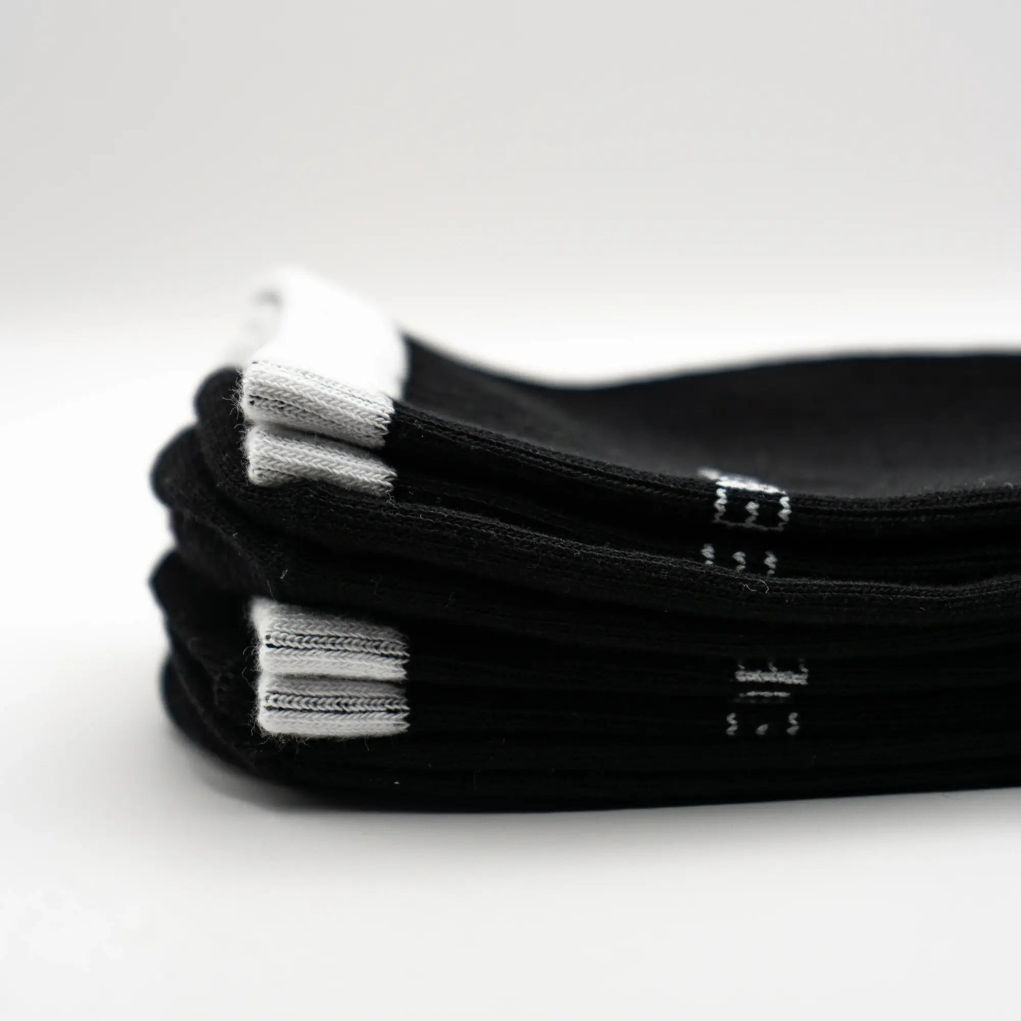 Stack of black socks with white brand label and white cuffs