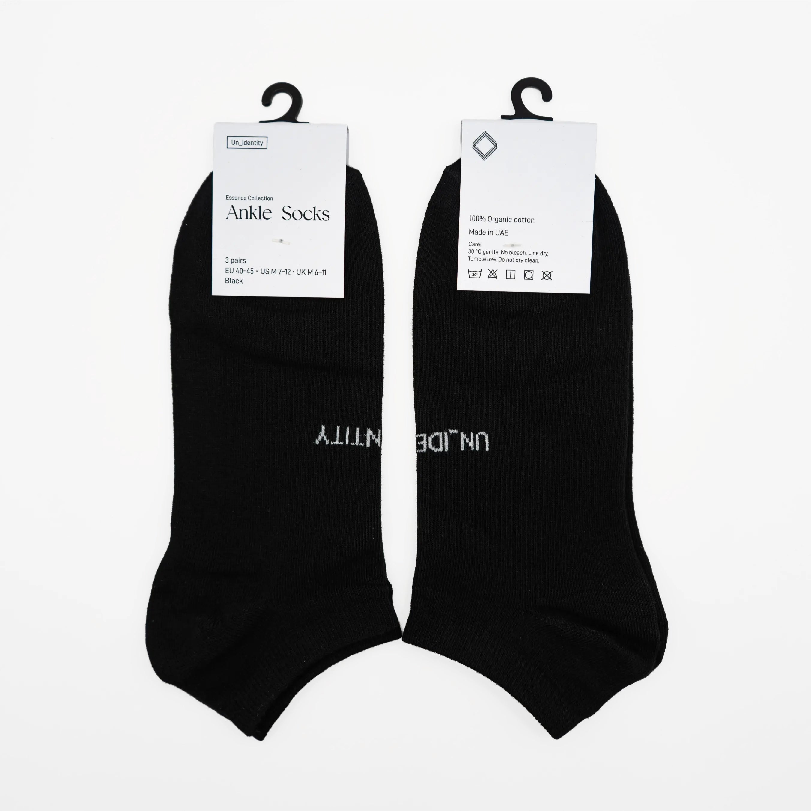 Two black ankle socks on hangers with 'Undecent' branding on a white background. #color_black