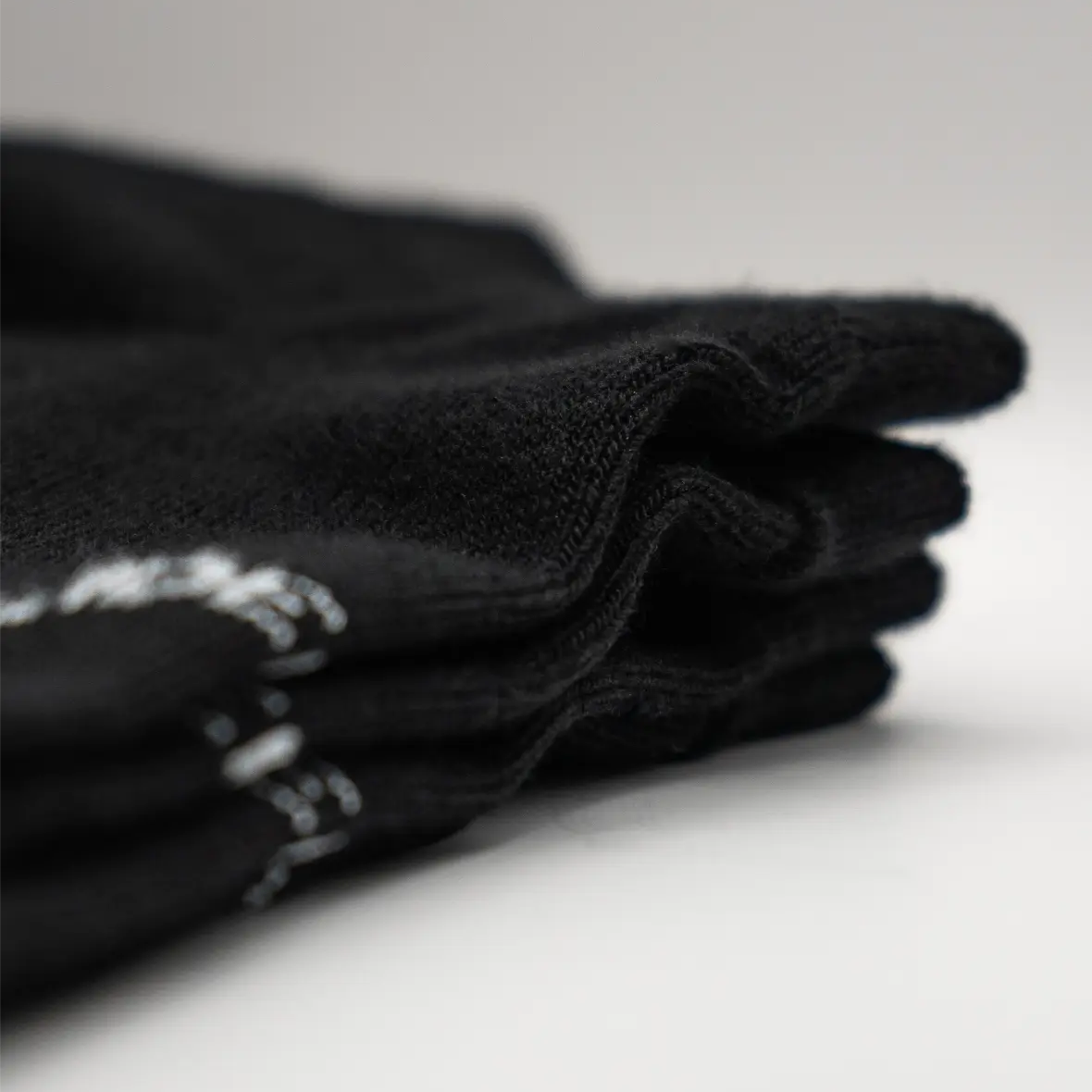 Stack of black socks with white text. #color_black