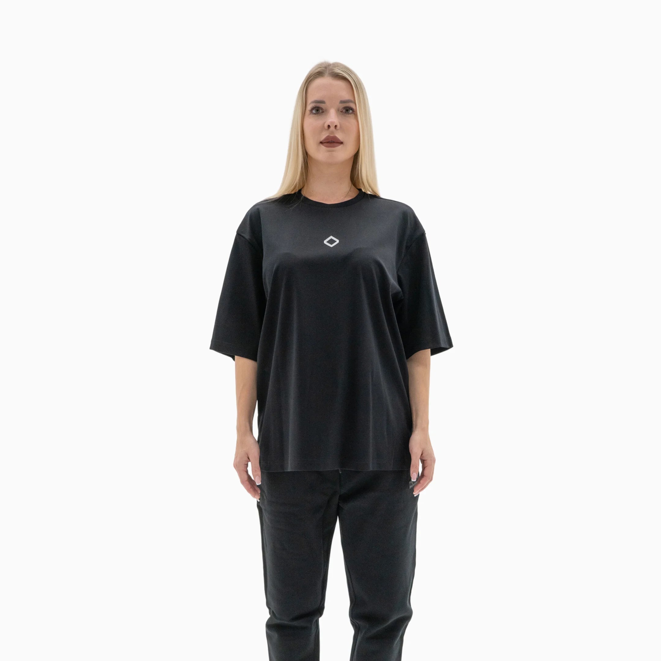 Person wearing a black t-shirt with a white logo on the chest against a plain background. #color_black