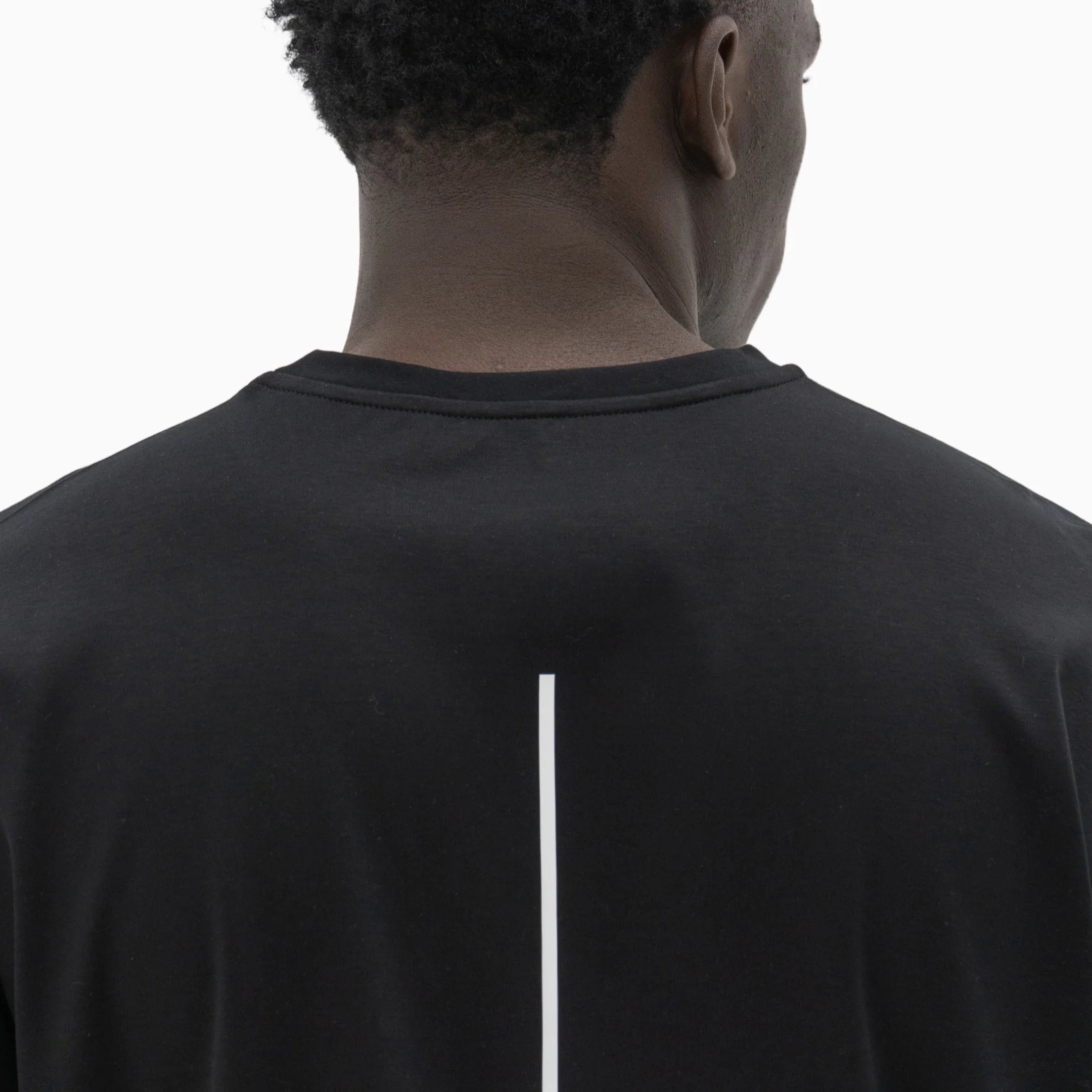 Person wearing a black t-shirt with a white line on the back against a plain background. #color_black