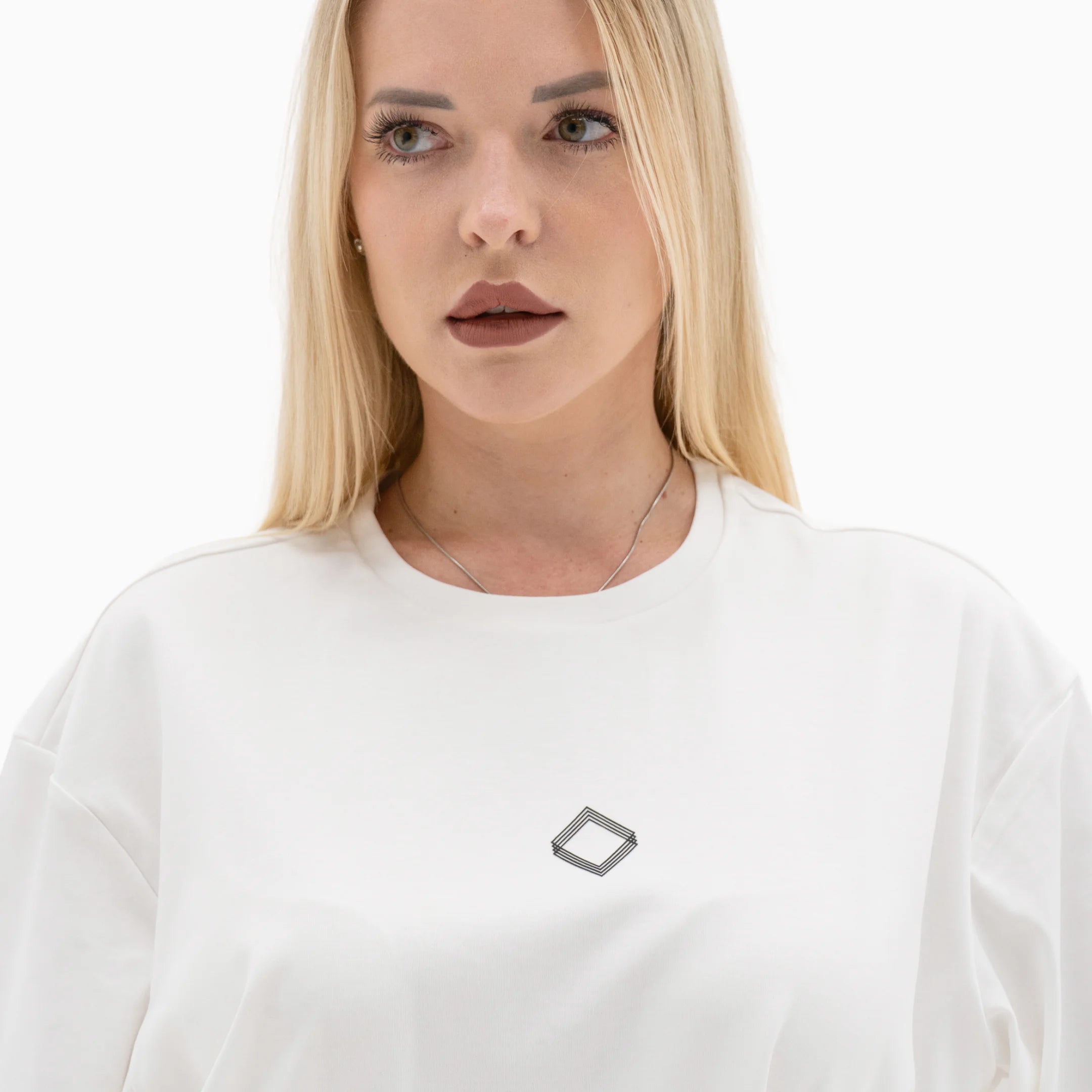 Person wearing a white t-shirt with a black logo on the chest against a plain background. #color_white