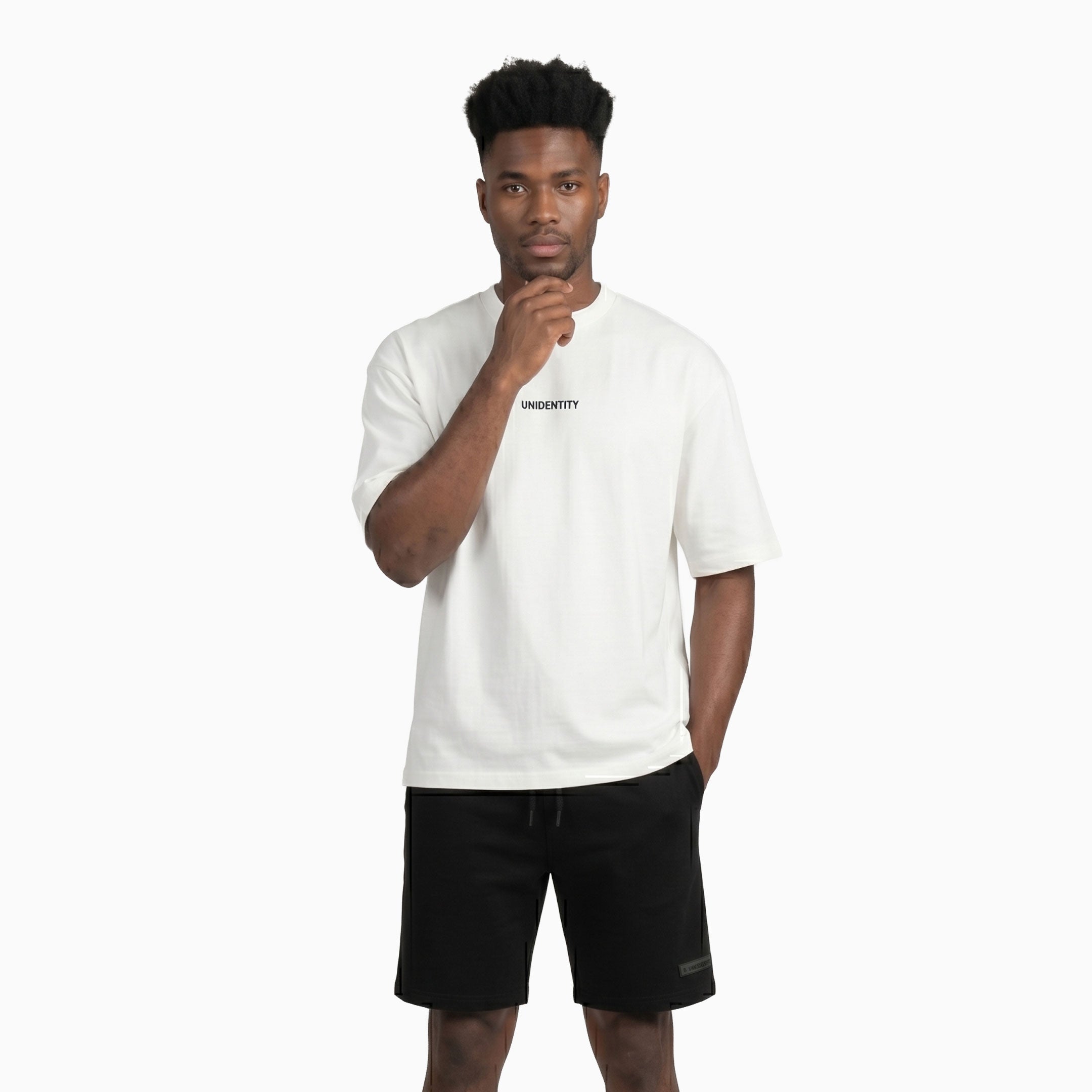 Man wearing a white t-shirt with 'UNIDENTITY' text and black shorts on a white background #color_white
