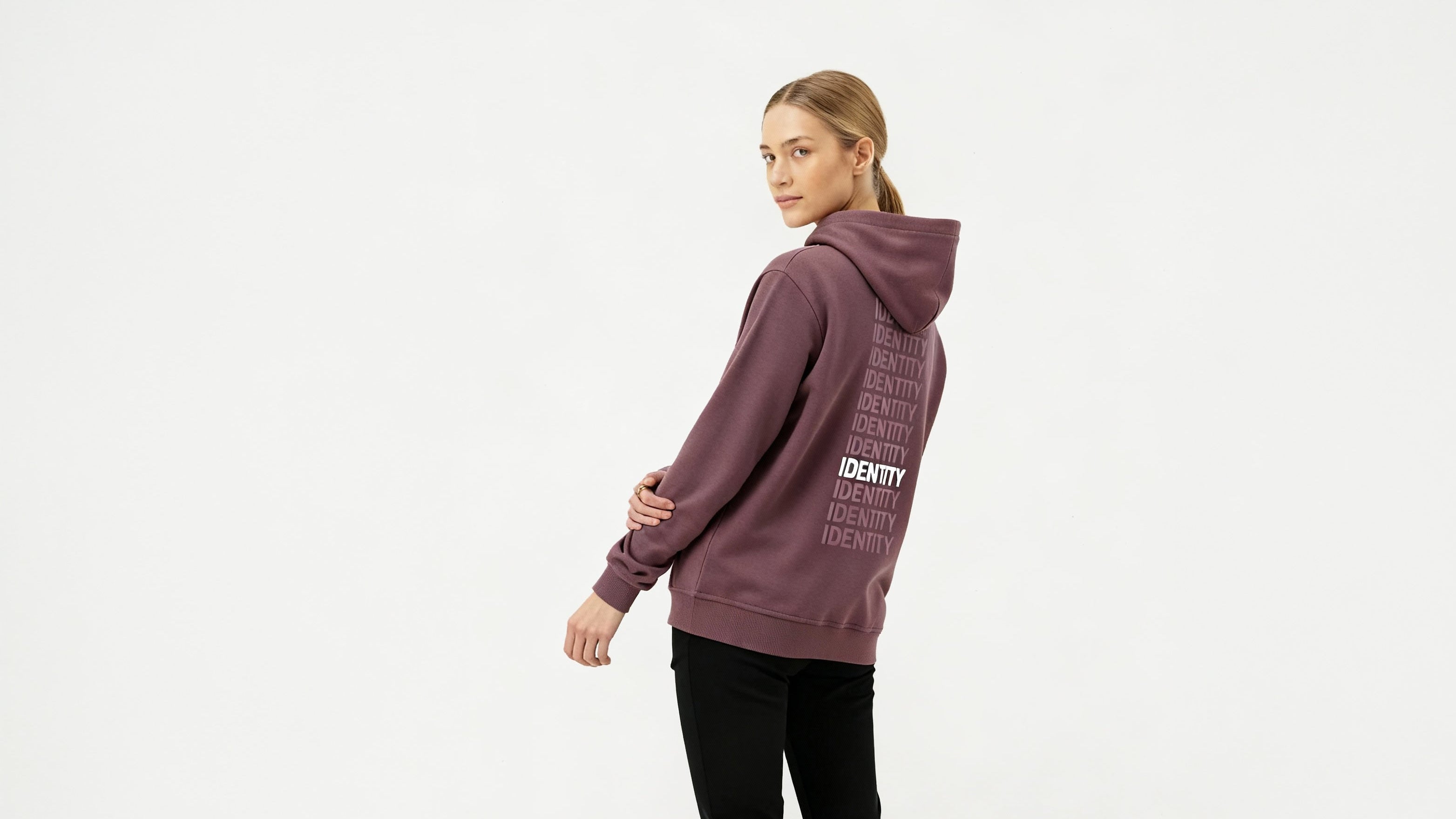 Person wearing a maroon hoodie with text on the back, standing against a white background