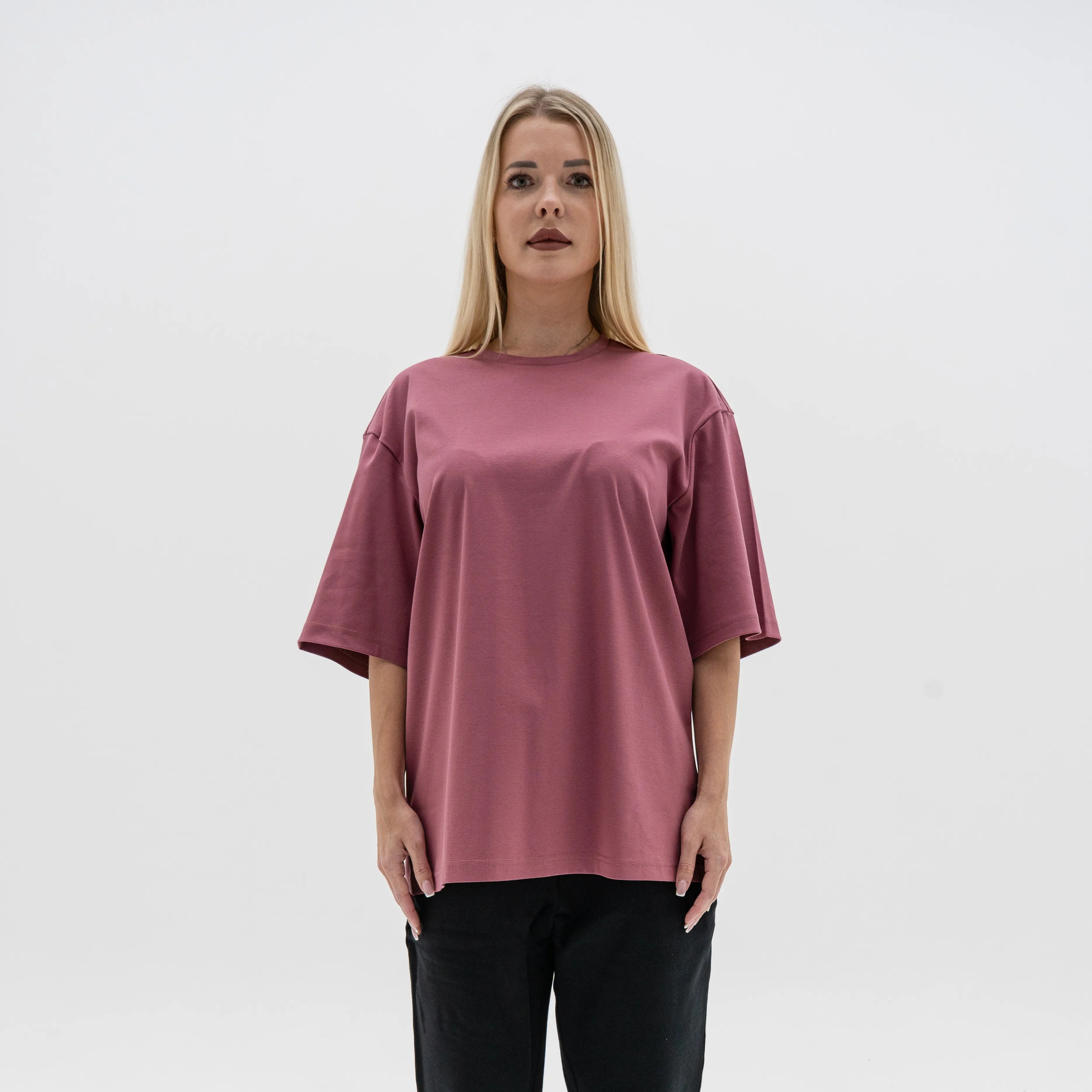 Woman wearing a mauve oversized t-shirt against a plain background. #color_plum