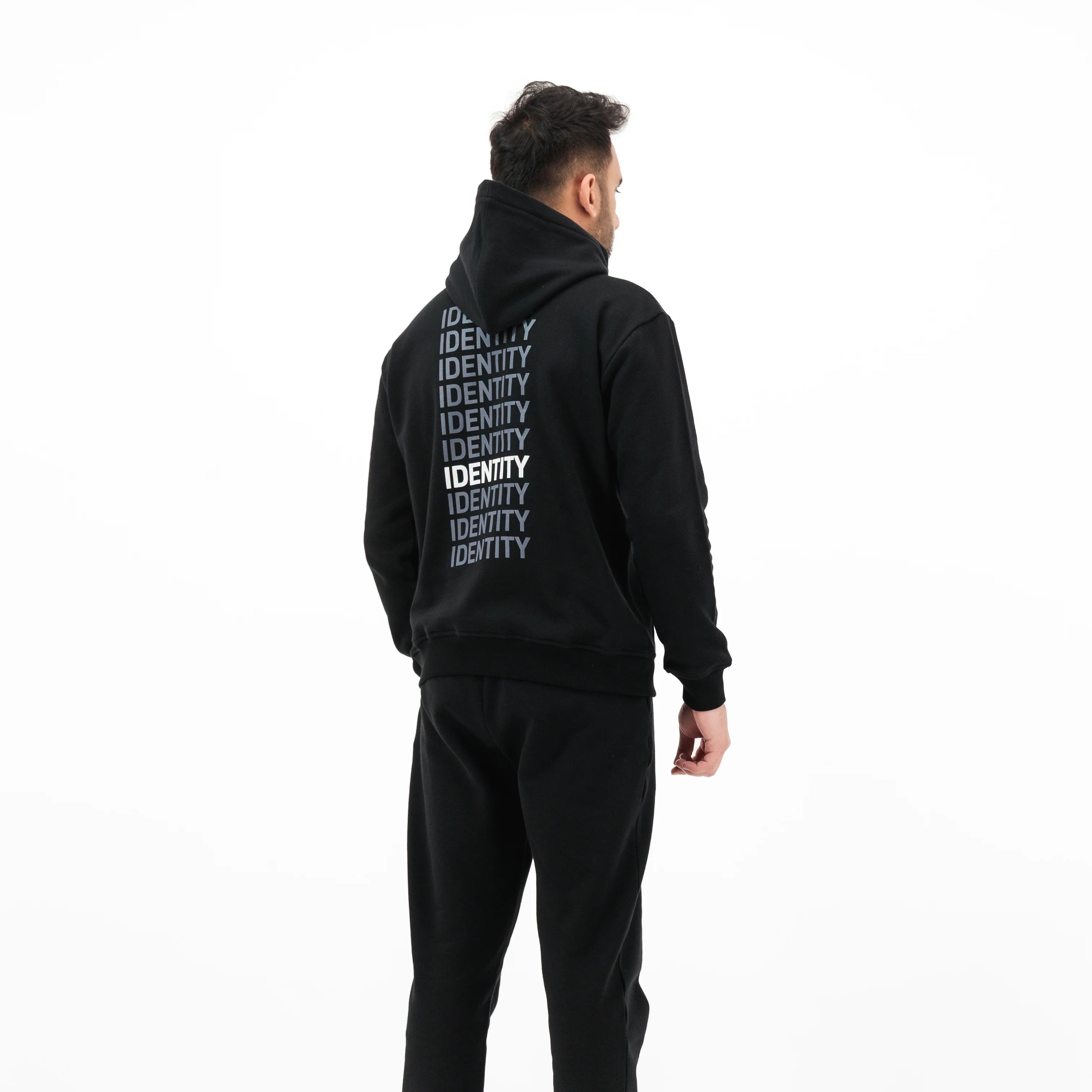 Model wearing black hoodie with text on the back and black pants
